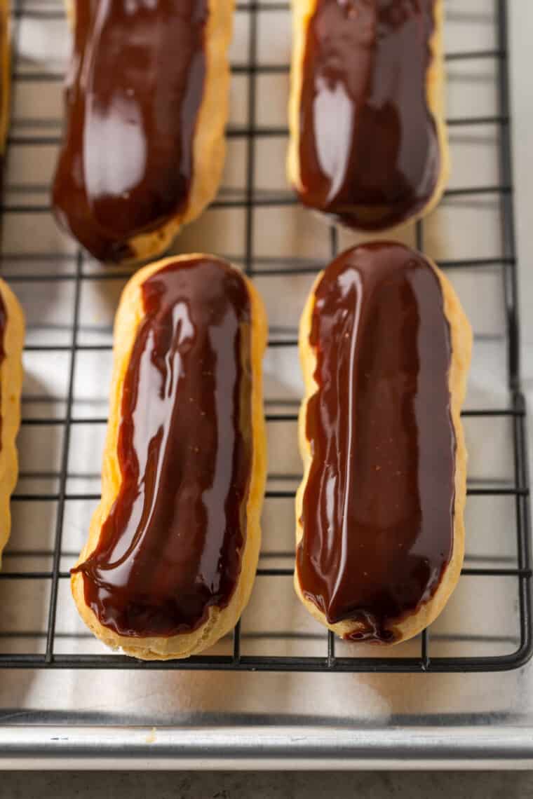 Chocolate dipped gluten-free eclairs on a wire rack.