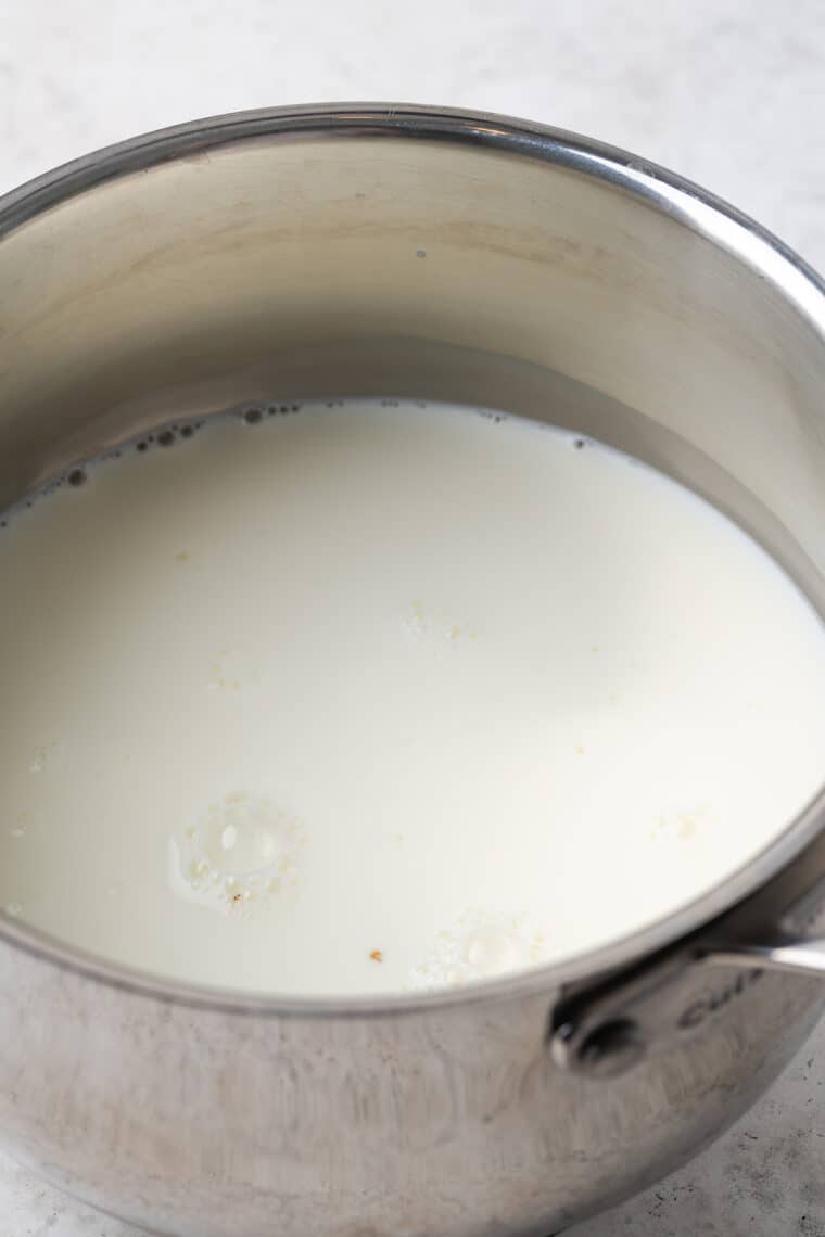 Hot milk steeped with vanilla bean paste in a saucepan.