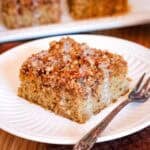 A slice of crumb-topped pumpkin cake on a plate next to a fork.