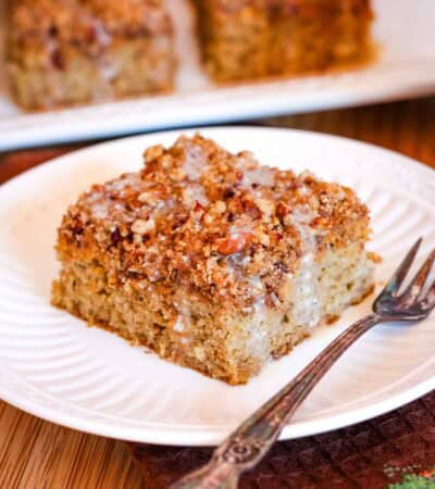 A slice of crumb-topped pumpkin cake on a plate next to a fork.