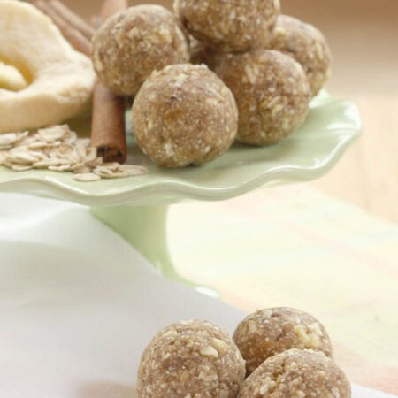 Three apple cinnamon bites on a napkin with more on a stand in the background.