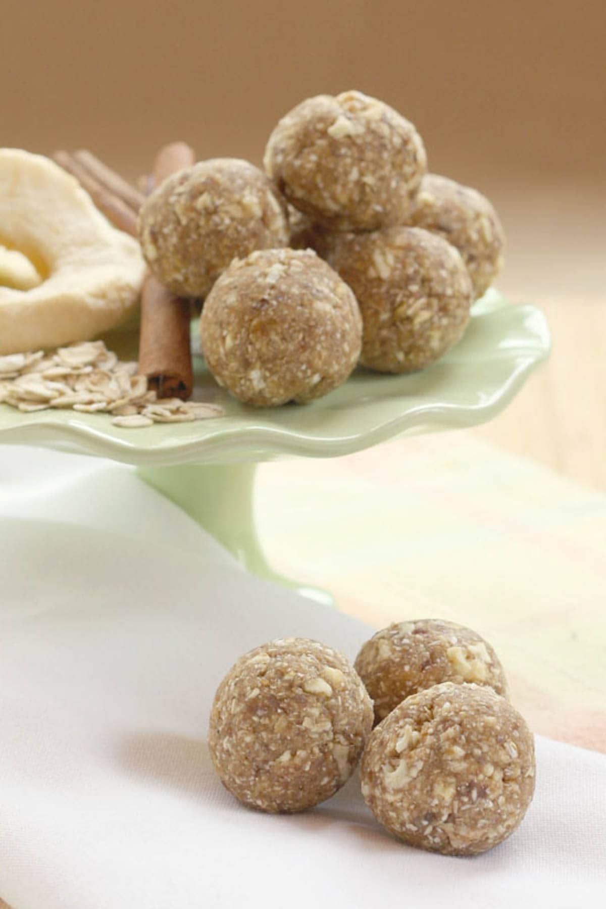 Three apple cinnamon bites on a napkin with more on a stand in the background.
