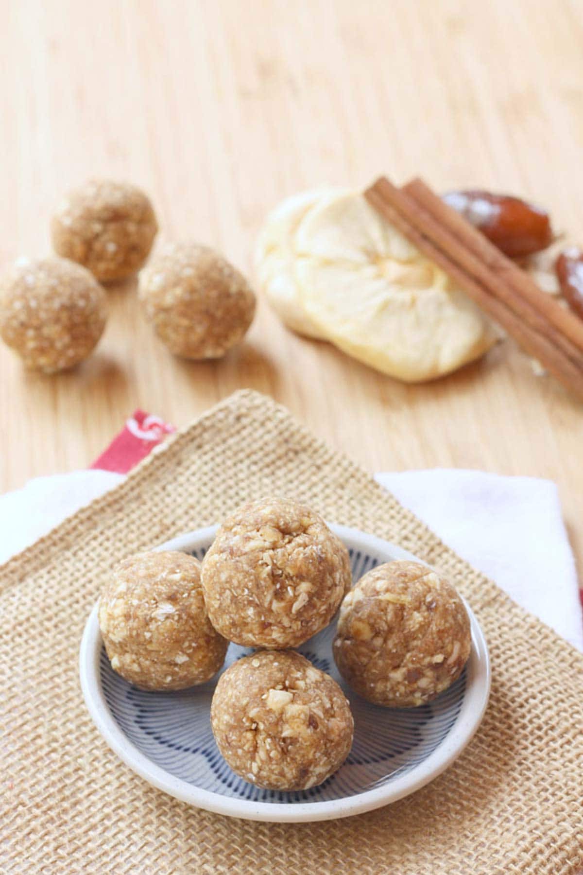 Cinnamon Apple Energy Balls on a small dish with more plus the ingredients in the background.