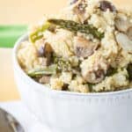 A bowl of quinoa with asparagus and mushrooms mixed in with text overlay that says "Roasted Asparagus Mushroom Quinoa Pilaf".