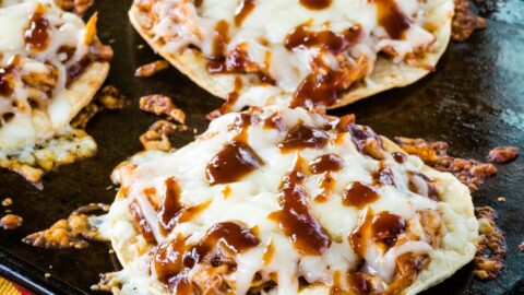 BBQ Chicken Tostadas covered with melted cheese on a sheet pan with some of the pieces of cheese melted and browned.
