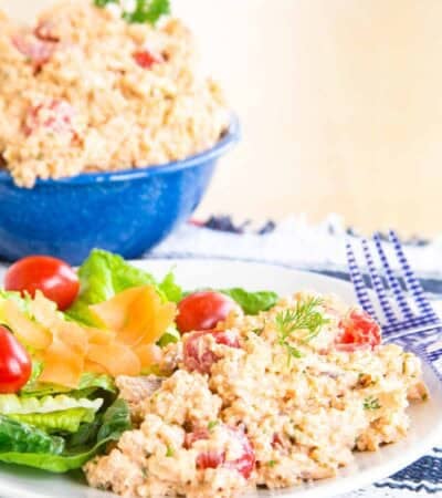 Quinoa salad with tomatoes in it with a side green salad on a plate.