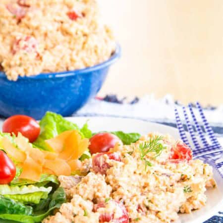 Quinoa salad with tomatoes in it with a side green salad on a plate.