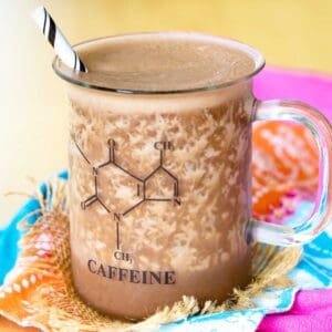 A chocolate almond coffee smoothie in a glass mug with a caffeine molecule on it.