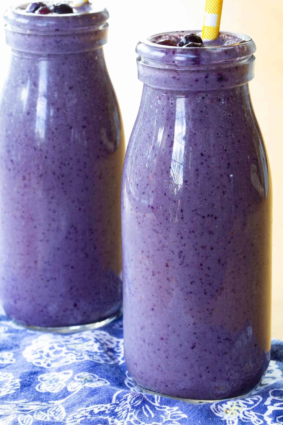 Two Blueberry Almond Butter Smoothies in glass bottles.