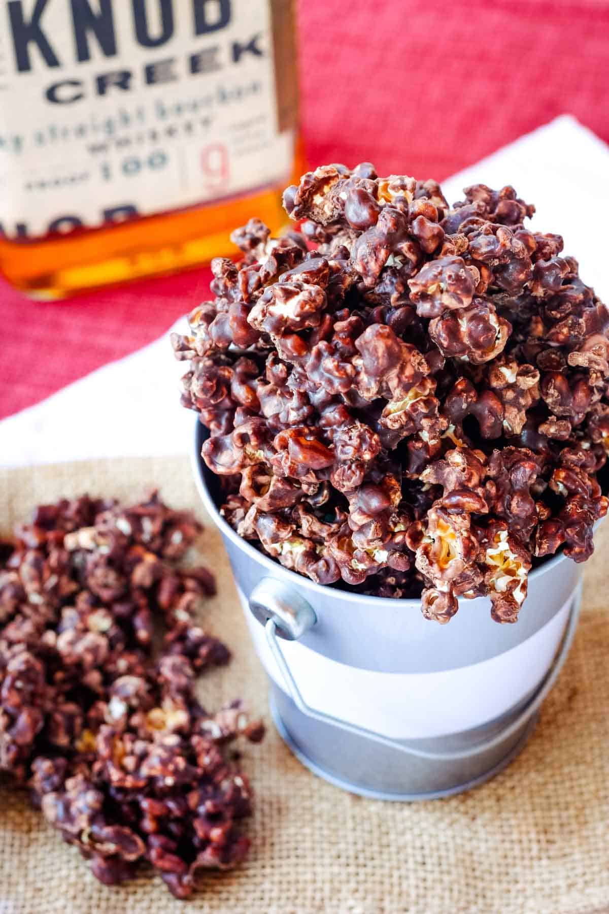 A bucket of bourbon chocolate-covered popcorn overflowing in a metal bucket.