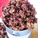 Chocolate-covered popcorn overflowing from a bucket with text overlay that says "Bourbon Chocolate Popcorn".