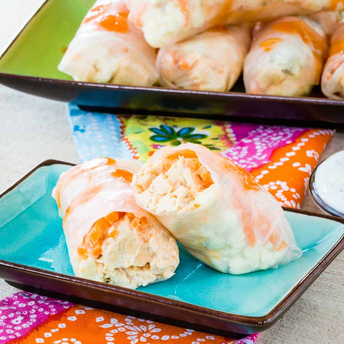 A buffalo chicke summer roll cut in half on a small blue plate.
