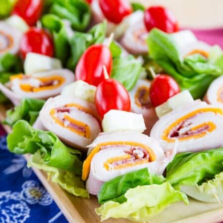 A wooden platter of Chef Salad on a Stick appetizers.