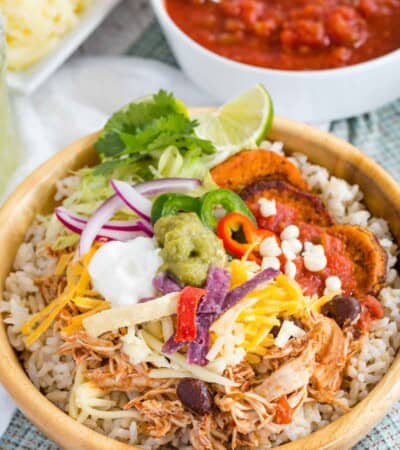 A Mexican chicken rice bowl with a bowl of salsa behind it.