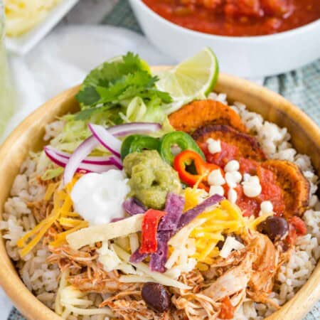 A Mexican chicken rice bowl with a bowl of salsa behind it.