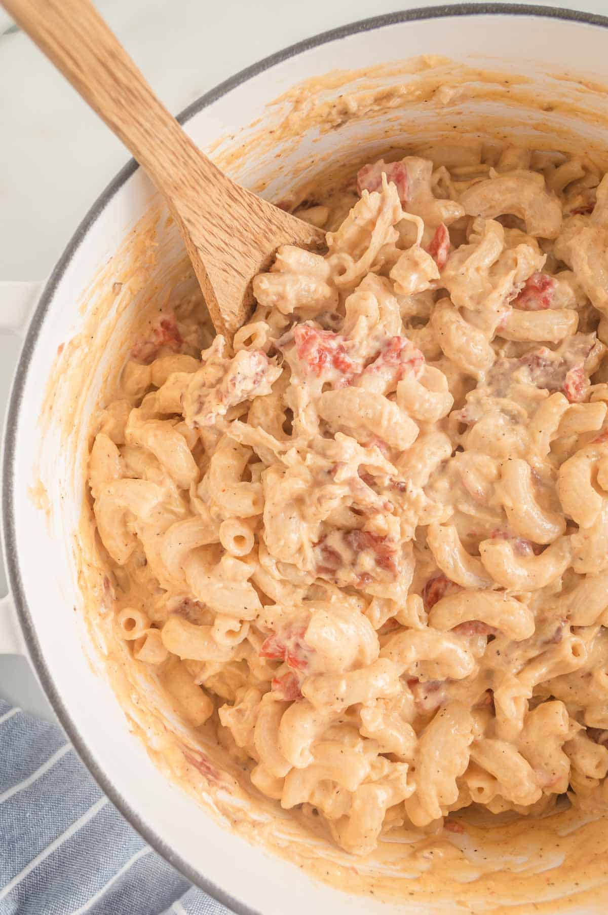 A wooden spoon stirring a pot of stovetop mac and cheese.