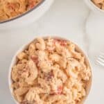 An overhead view of a bowl of finished mac and cheese with bacon and chicken sprinkled with pepper.
