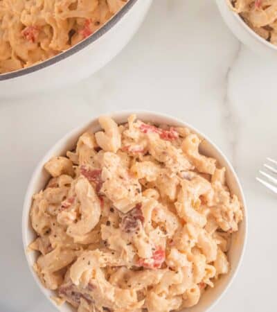 An overhead view of a bowl of finished mac and cheese with bacon and chicken sprinkled with pepper.