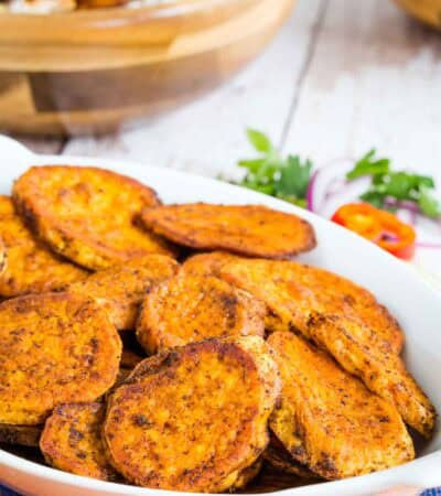 Sliced Roasted Sweet Potatoes coated in chili powder in a serving dish.