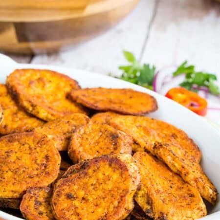 Sliced Roasted Sweet Potatoes coated in chili powder in a serving dish.