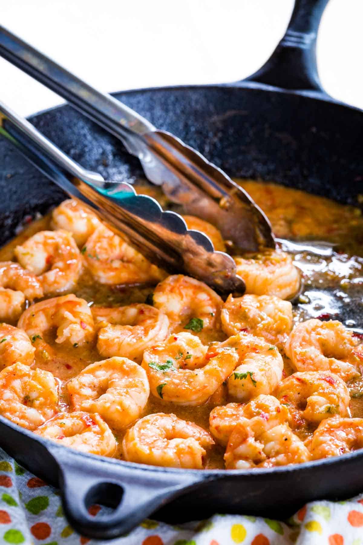 Honey Lime Shrimp in a Cast Iron Skillet with Tongs.