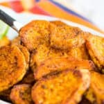 A dish of roasted sweet potatoes with text overlay that says "Spicy Baked Sweet Potato Slices".