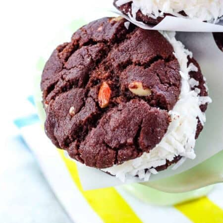 A closeup of a chocolate cookie ice cream sandwich with the edges rolled in coconut.