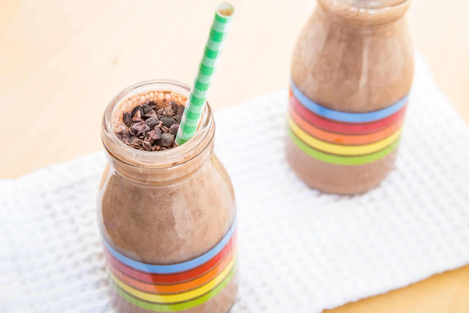 A Chocolate Mint Smoothie in a glass bottle with a straw in it.