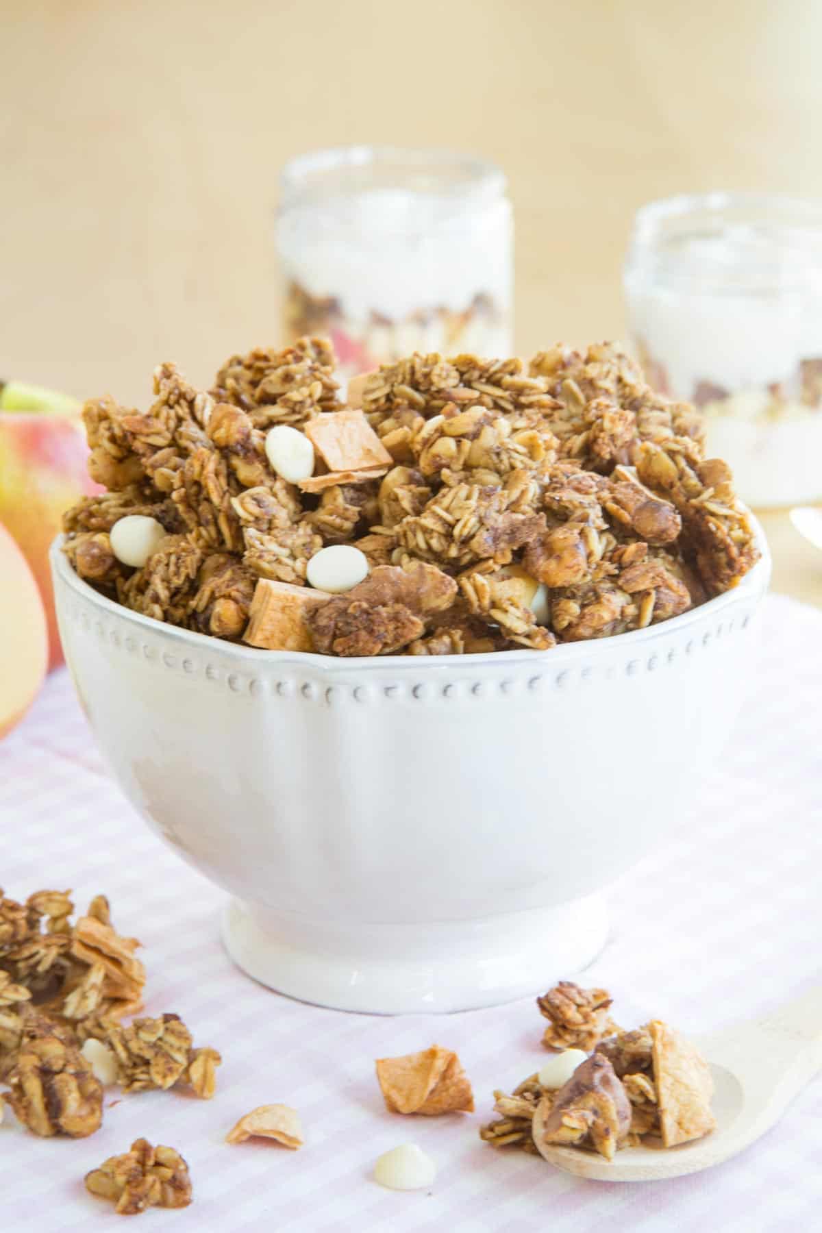 Cinnamon Apple Granola in a bowl with yogurt parfaits in the background.