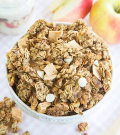 Looking down at a bowl of granola with clusters, dried apples, and white chocolate chips