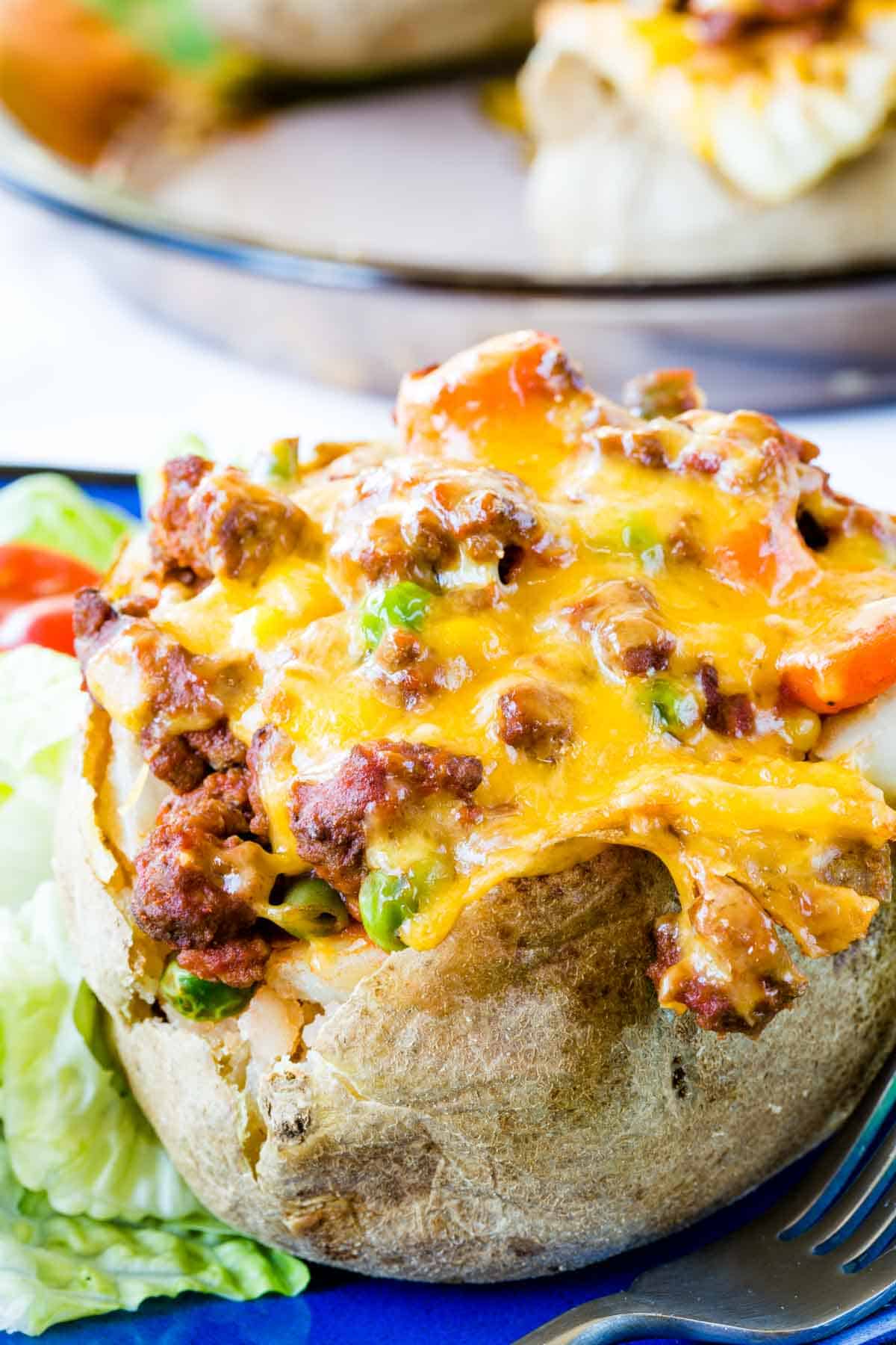 A closeup of a baked potato stuffed with ground beef and vegetables and topped with melted cheddar cheese.