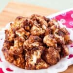 A white plate of cauliflower bites with text overlay that says "Cranberry Balsamic Glazed Cauliflower".