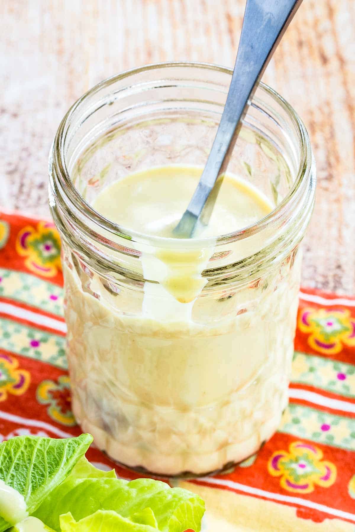 A jar of creamy salad dressing with a spoon in it.