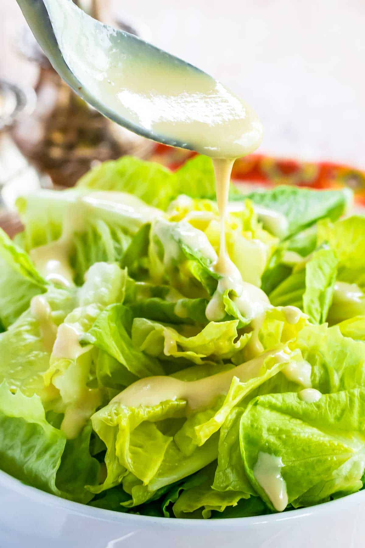 Creamy Maple Dijon Dressing dripping off of a spoon onto lettuce.