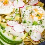 A skillet of tortilla chips cooked in salsa verde topped with fried eggs, avocado, queso fresco, and radish slices with text overlay that says, "Quick and Easy Chilaquiles Verdes".