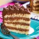 A slice of gluten free layer cake with chocolate buttercream on a plate with a fork.
