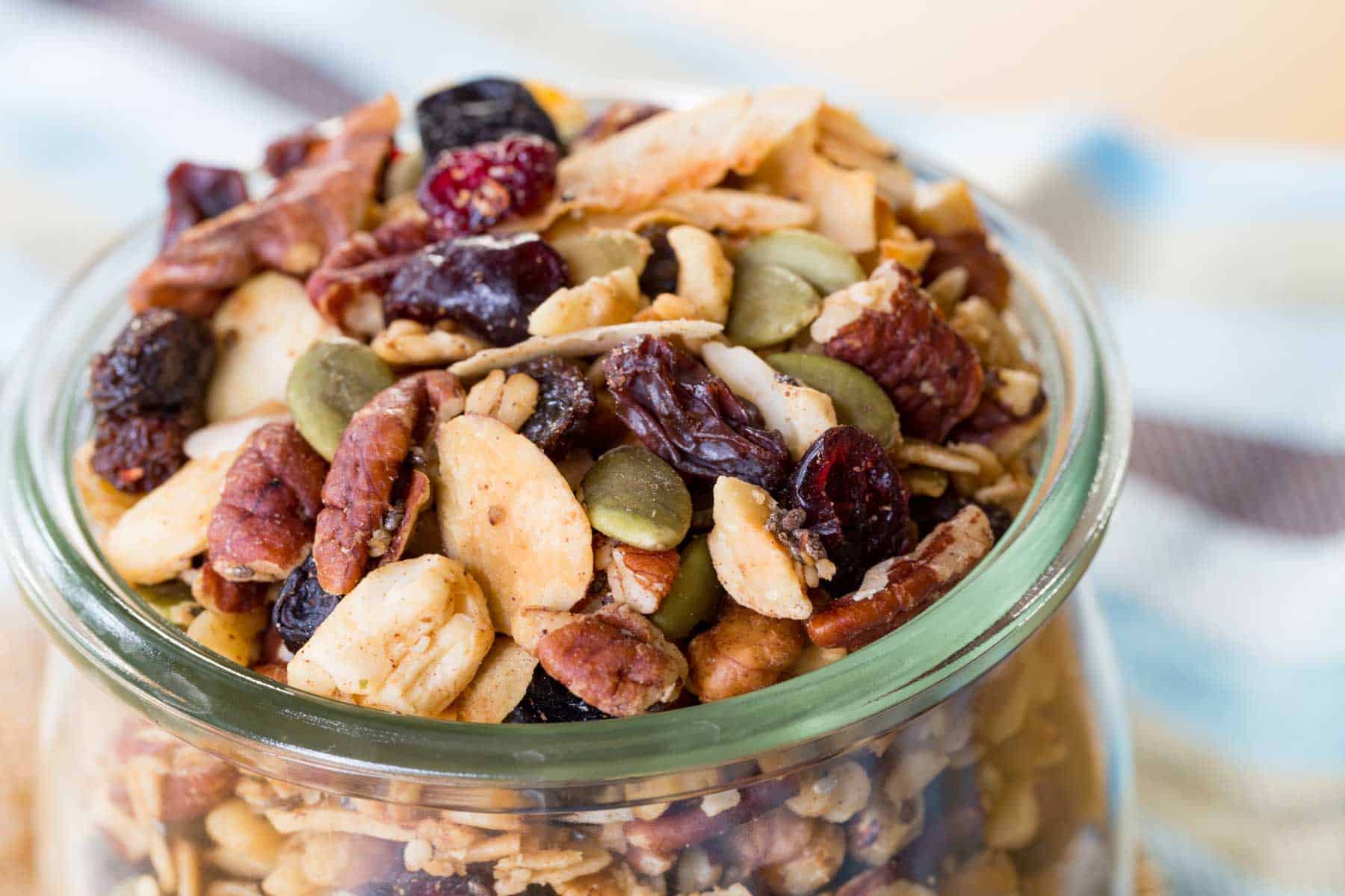 Looking in at the top of a full jar of granola with lots of nuts.
