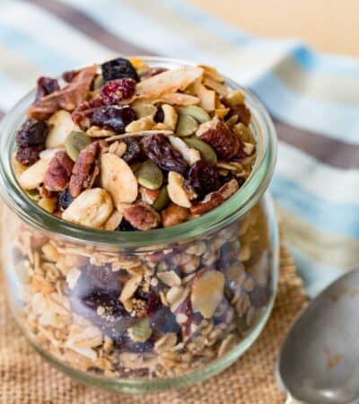 Granola in a jar with a spoon lying next to it.