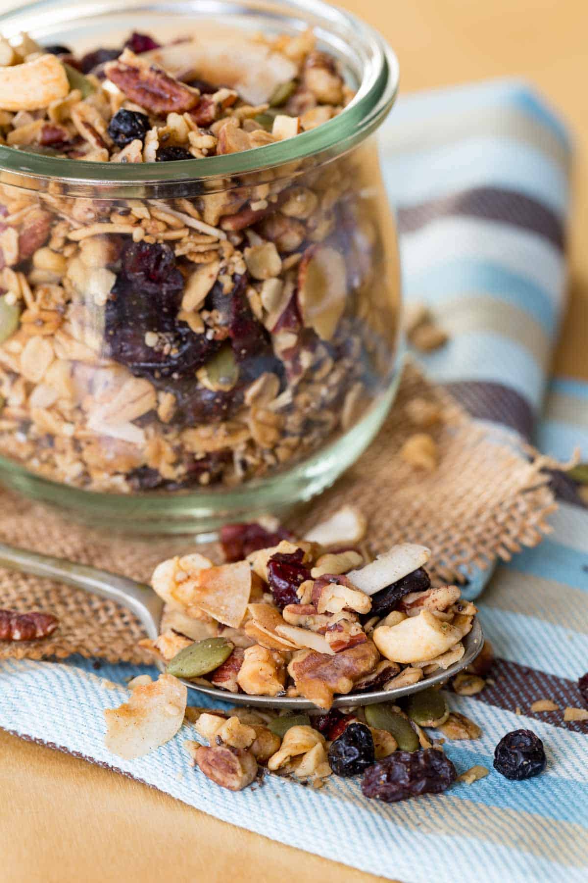 A spoonful of granola on a striped napkin with a full jar behind it.