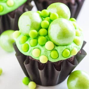 A Halloween chocolate cupcake with green frosting and sugar pearls.
