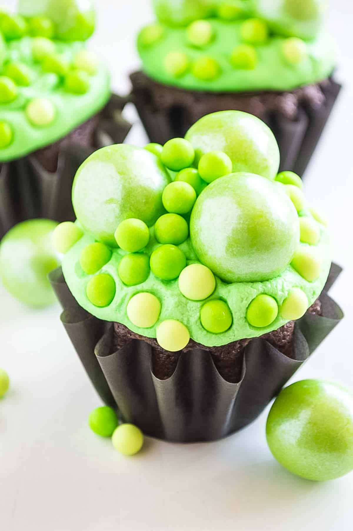 A Halloween cupcake decorated with green frosting and decorations.