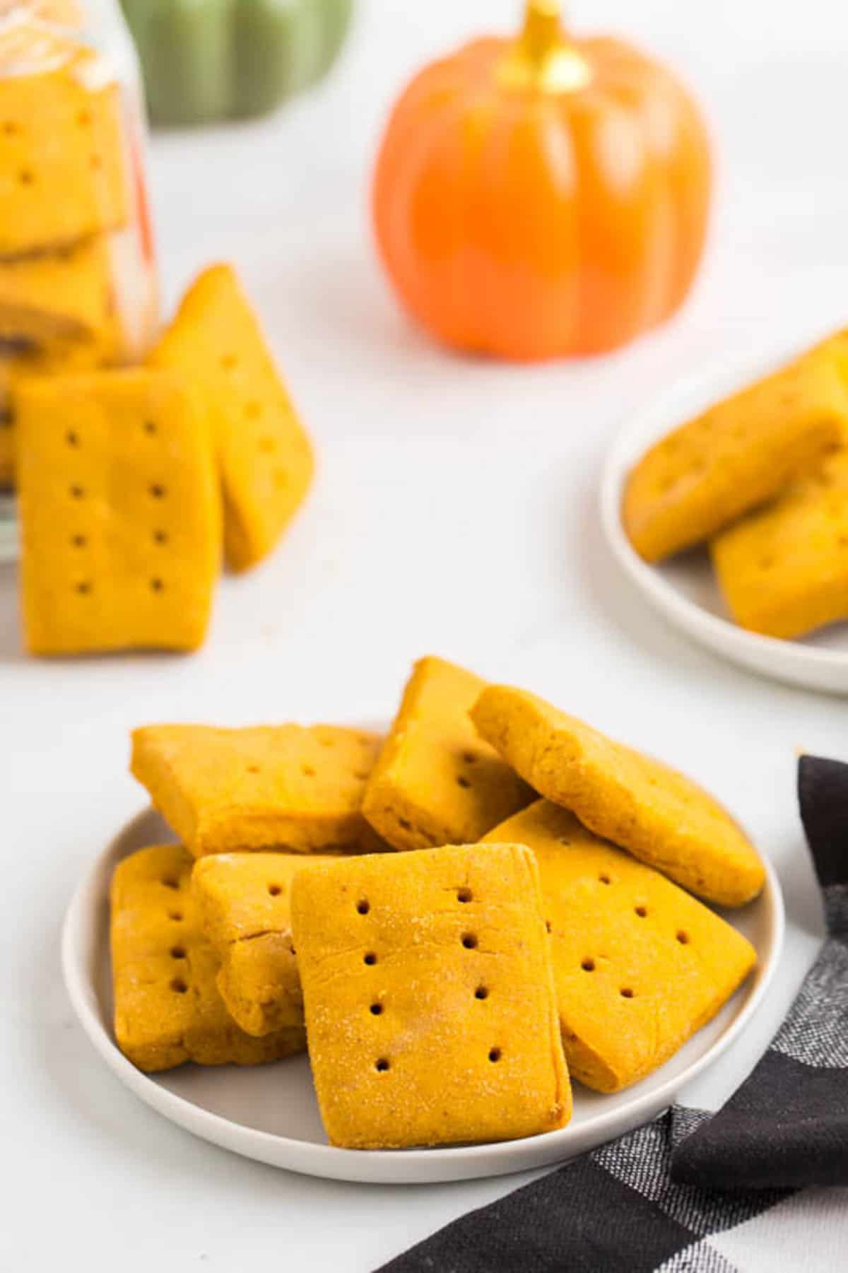 cookies stacked on a white plate with more on plates and in a jar in the background.