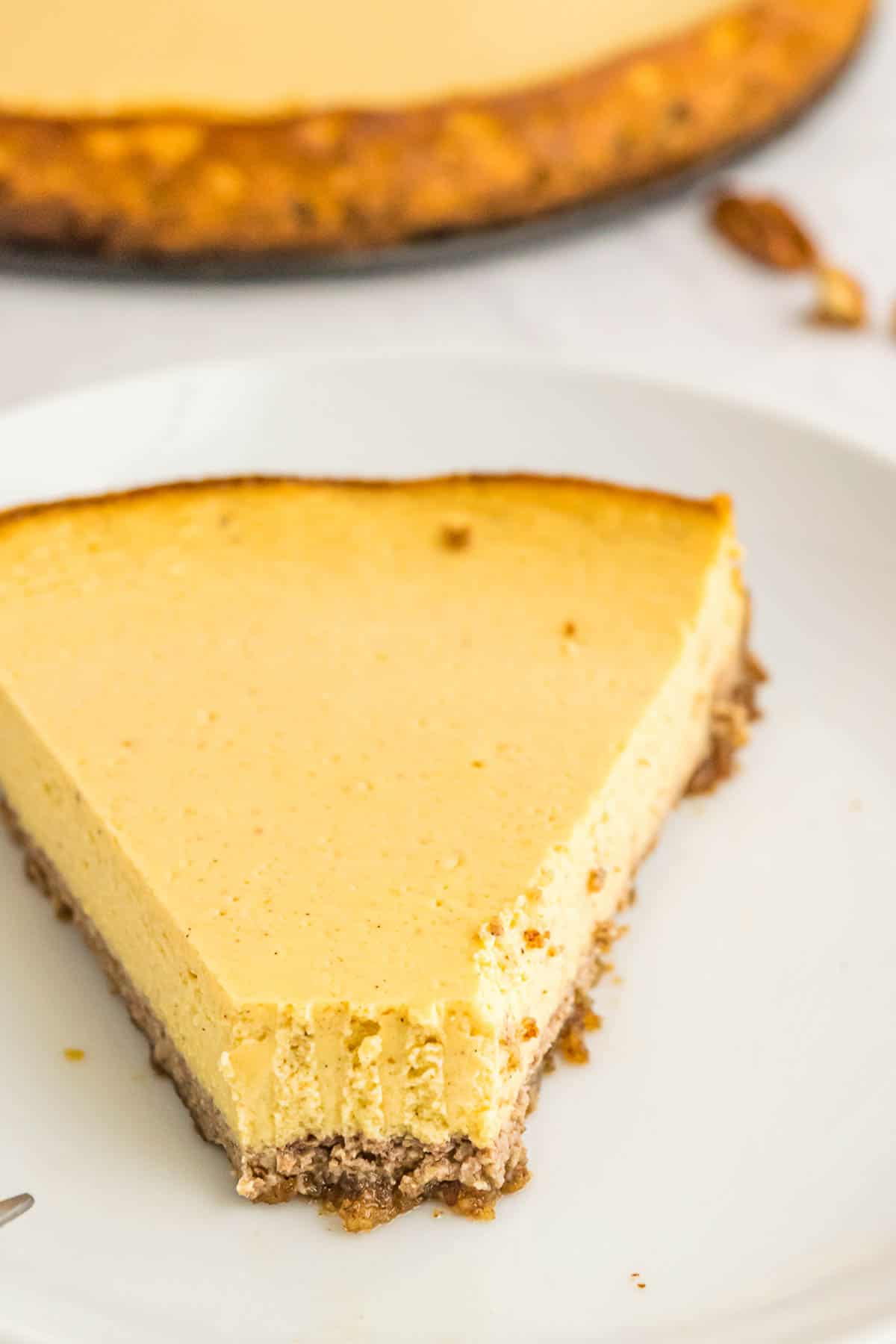 A slice of pumpkin cheesecake tart with a bite missing from the tip of the piece.