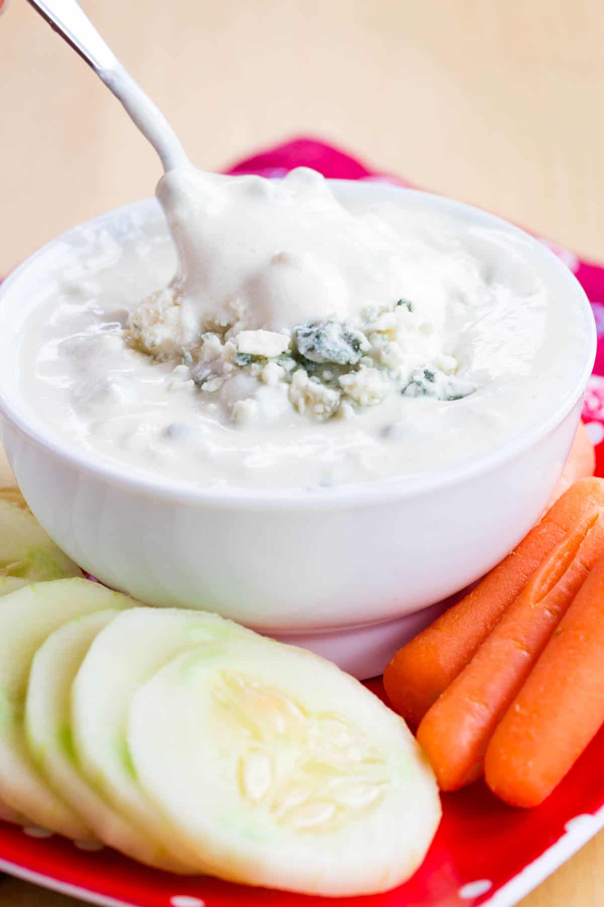 Blue cheese dip dripping off a spoon into the bowl of it.