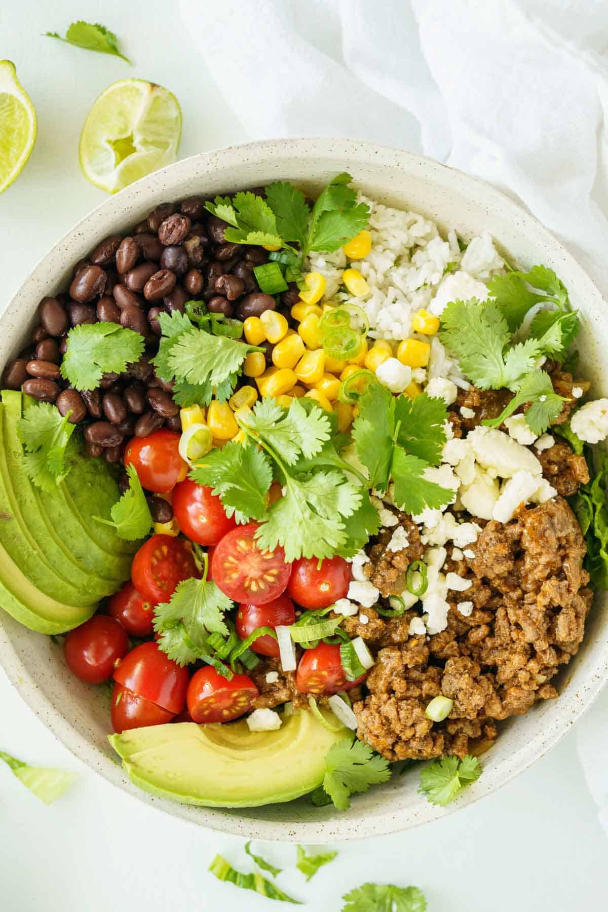 The Top View of a Beef Burrito Bowl Next to Two Lime Wedges.