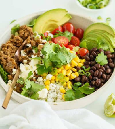 A Beef Burrito Bowl on a White Countertop Beside a White Dish Towel.