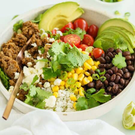 A Beef Burrito Bowl on a White Countertop Beside a White Dish Towel.