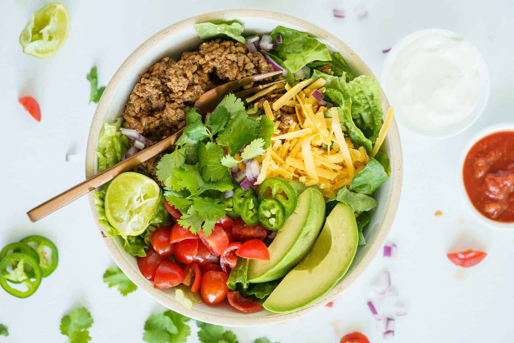 A birds eye view of a keto ground beef taco salad bowl with a gold-colored fork in it.