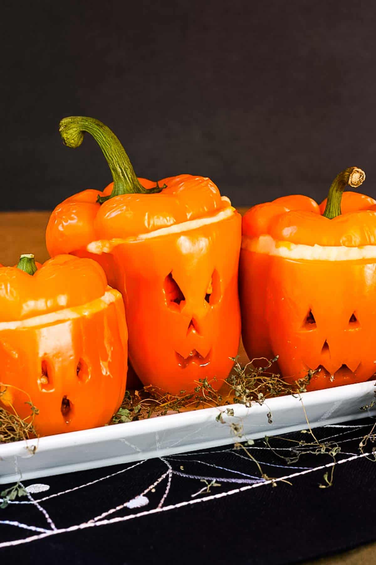 Jack o'lantern shepherds pie stuffed peppers on a white dish.