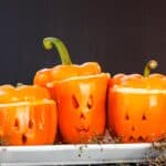 Three halloween stuffed peppers carved with jack o'lantern faces.